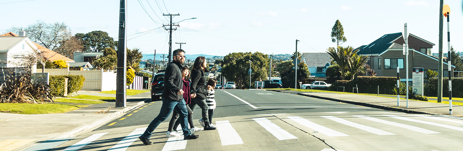 A family of four walk across a pedestrian crossing.