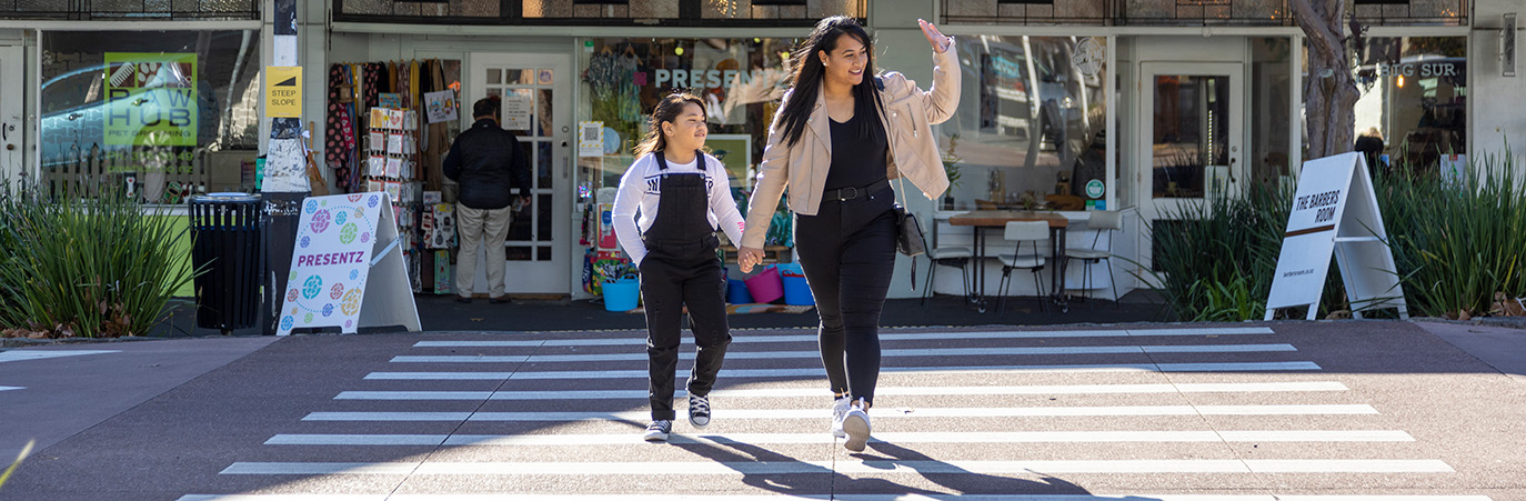Adult and child walk across pedestrian crossing.